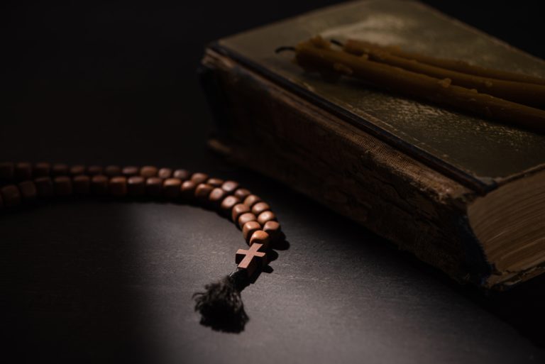 Selective Focus of Holy Bible With Candles And Rosary With Cross in Dark With Sunlight